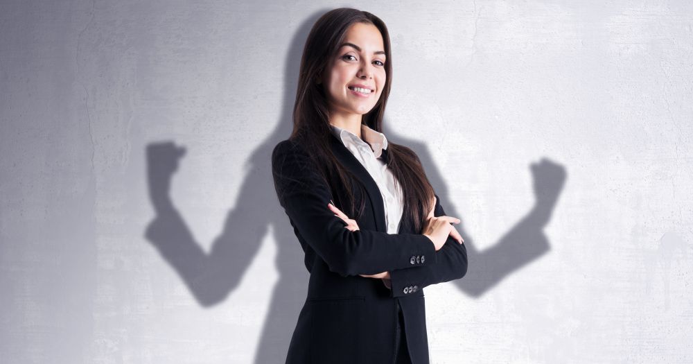 Kvinna med armarna i kors vars skugga spänner musklerna